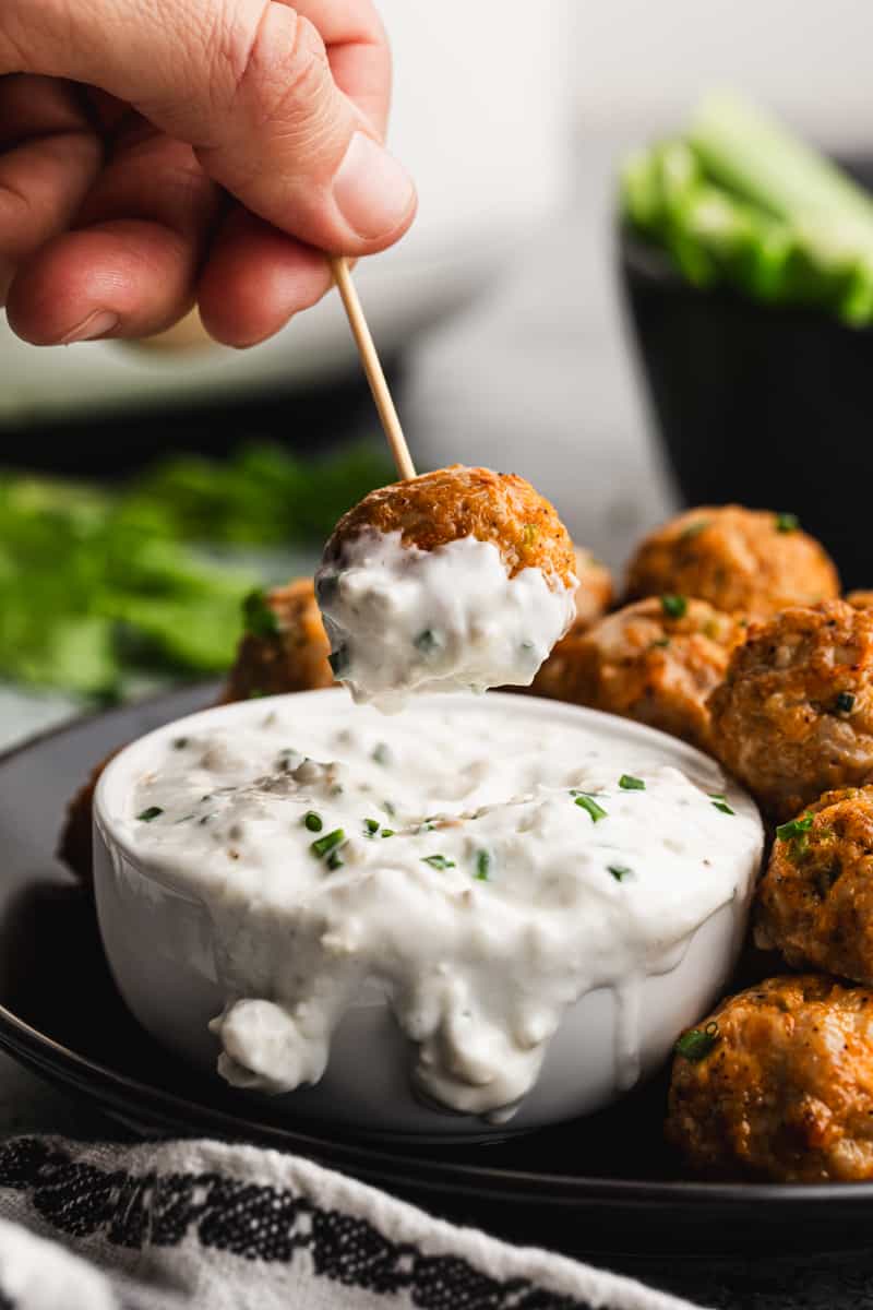 The BEST Buffalo Chicken Meatballs with one of them being dipped in a homemade bleu cheese dip.