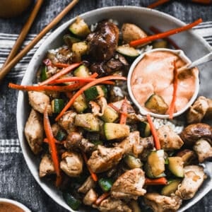 An easy Hibachi Chicken recipe with vegetables on a plate served over rice and with a side of homemade Yum Yum sauce.