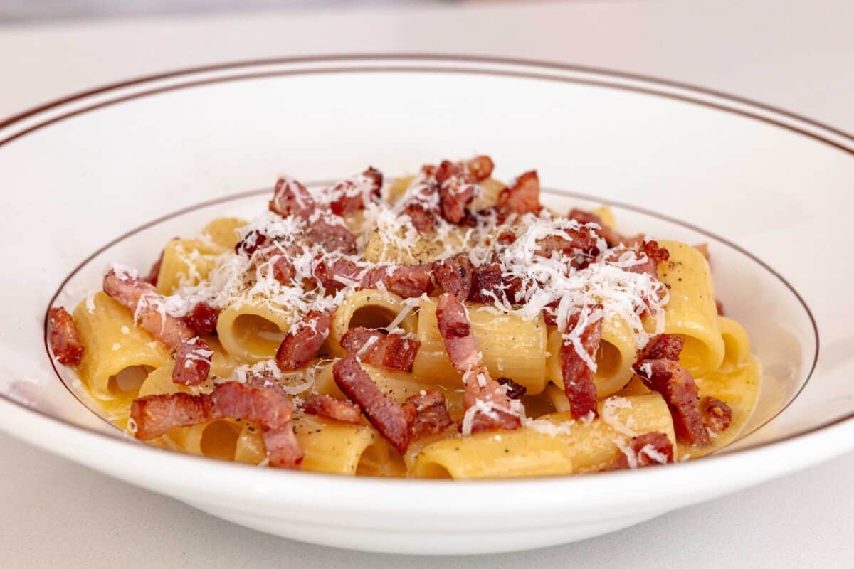 A plate of the best Pasta Carbonara topped with crispy pancetta, parmesan cheese, and black pepper. 