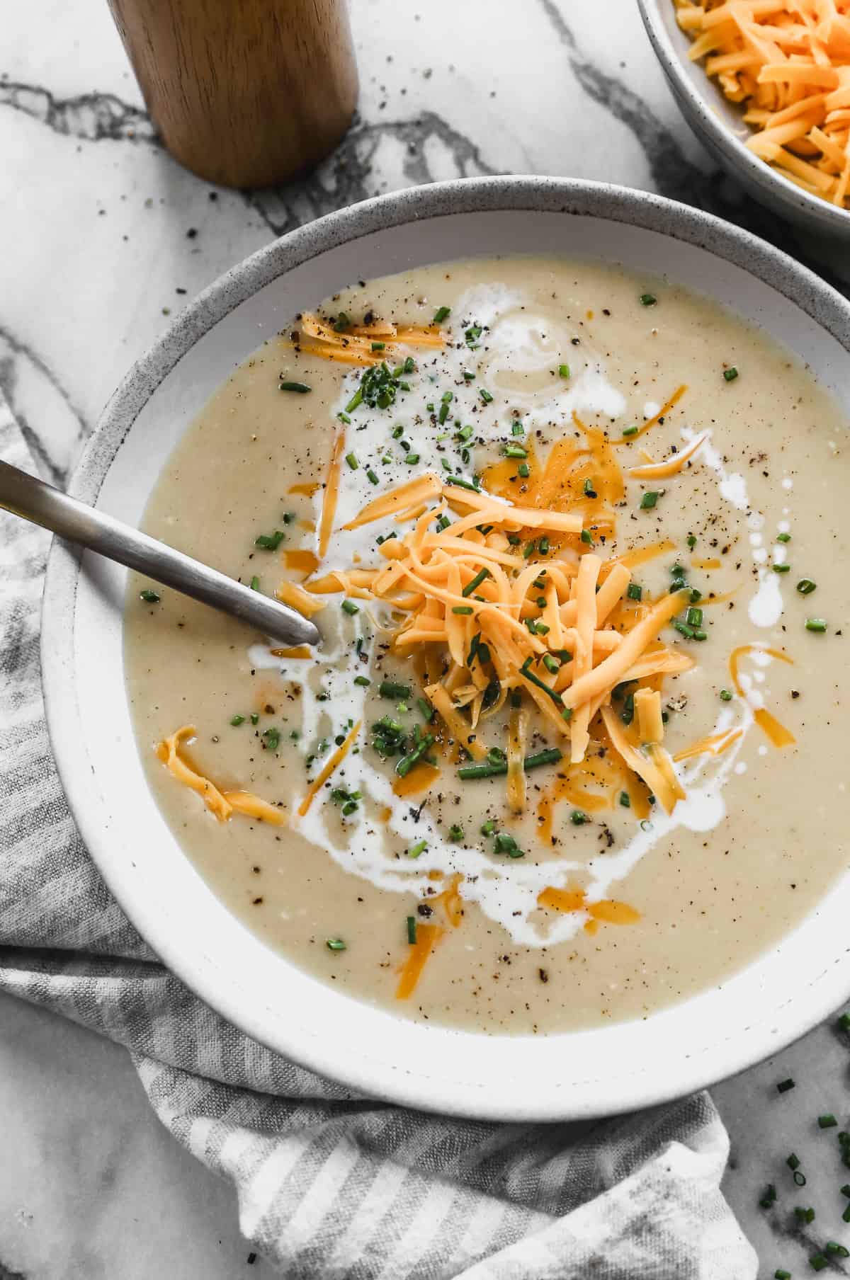 An easy Roasted Cauliflower Soup recipe topped with shredded cheese and chives.