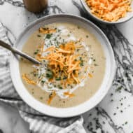 An easy Roasted Cauliflower Soup recipe topped with shredded cheese and chives.