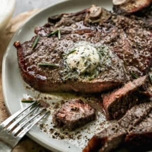 The best air fryer steak topped with homemade garlic butter with a piece cut to show the juicy interior.