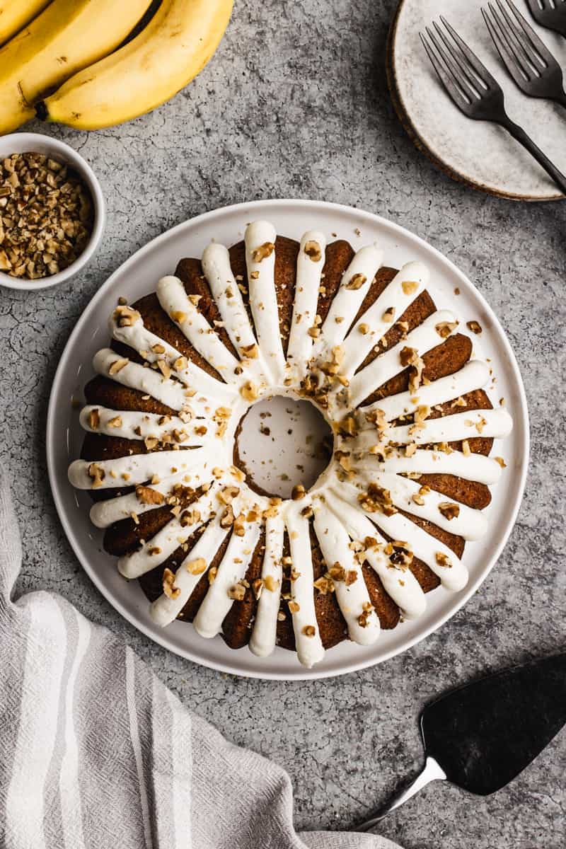 An easy Banana Bundt Cake recipe frosted with cream cheese frosting and sprinkled with chopped walnuts.