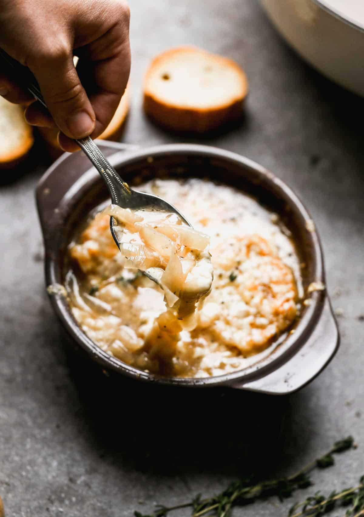 A spoon lifting up a bite of a simple French Onion Soup recipe.