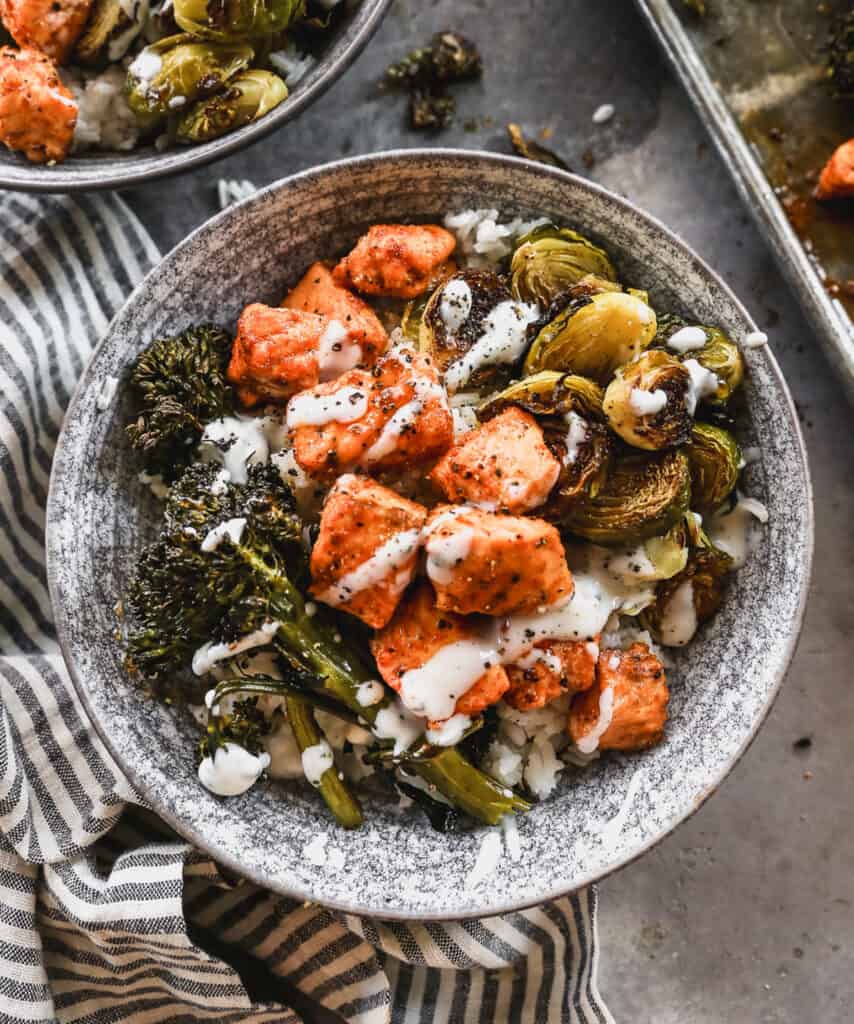 A homemade Hot Honey Salmon Bowl with salmon, broccolini, and brussels sprouts on a bed of rice.
