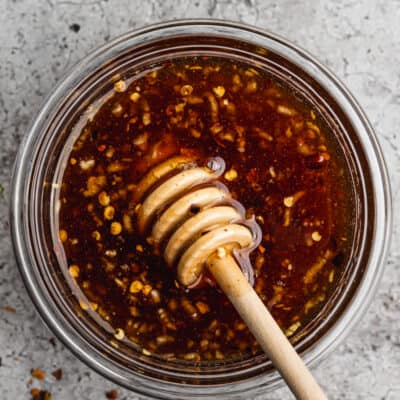 The best hot honey recipe in a glass dish with a honey dipper.