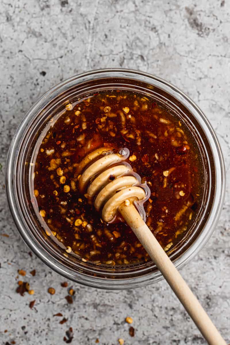 The best hot honey recipe in a glass dish with a honey dipper.
