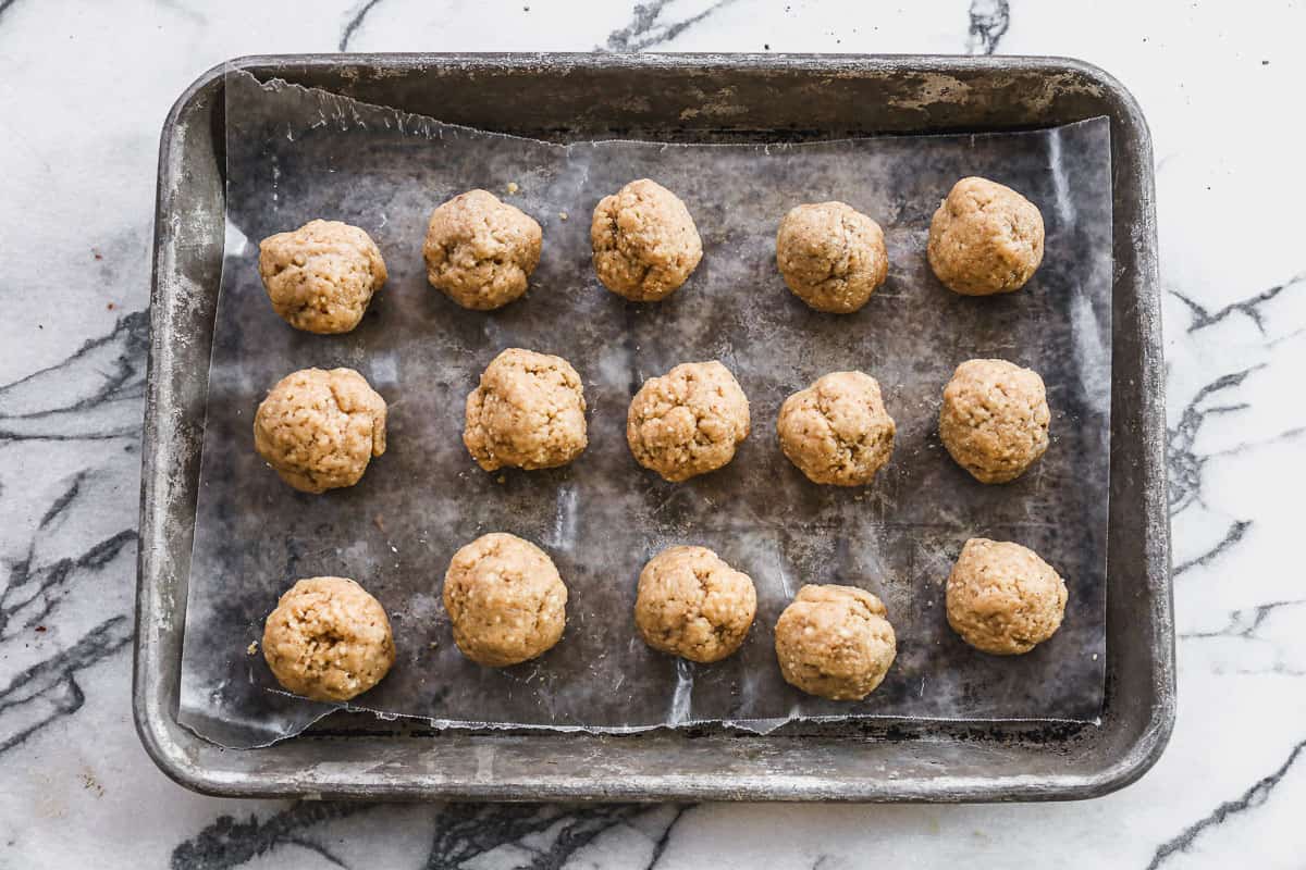 Easy matzo balls formed into balls and placed on a wax lined baking sheet.