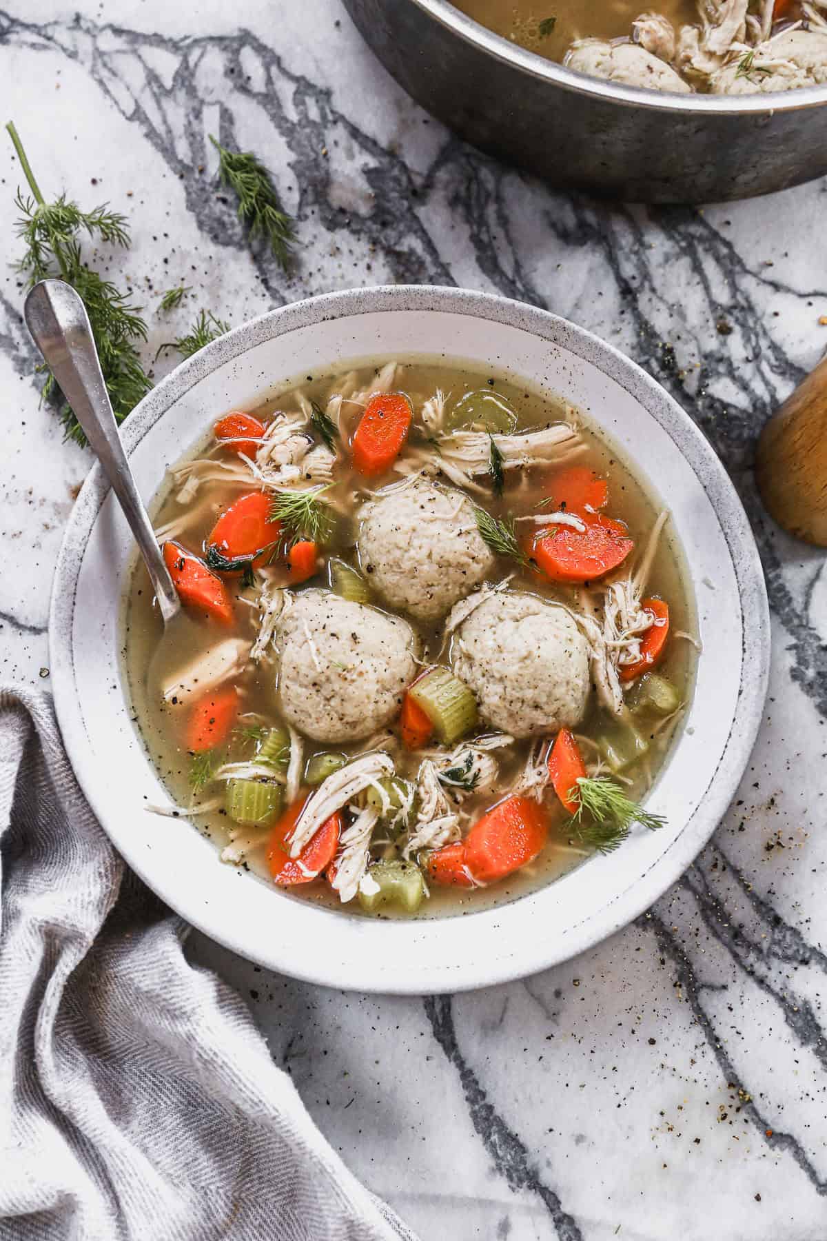 The best Matzo Ball Soup recipe served in a bowl with a flavorful broth with carrots, celery, and herbs and three matzo balls.