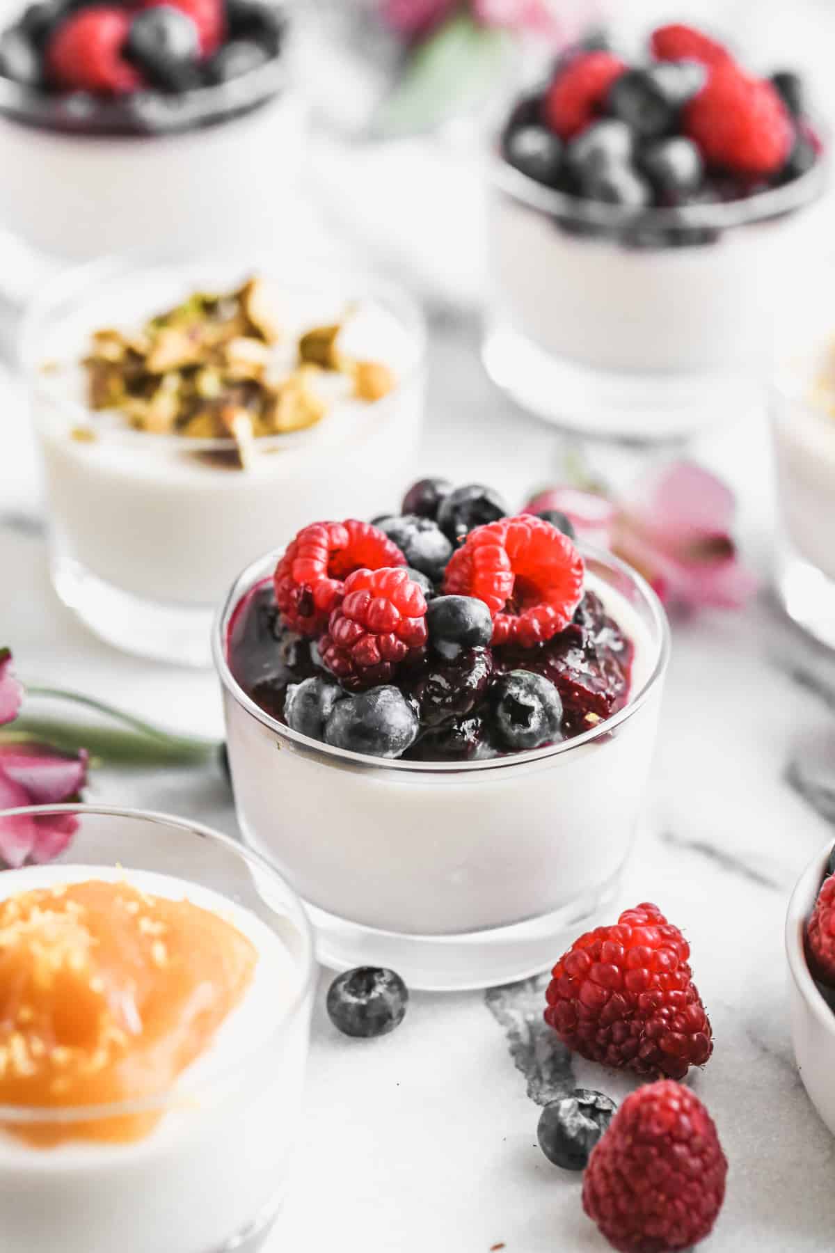 The best Panna Cotta recipe topped with a homemade berry sauce and fresh berries, ready to enjoy.