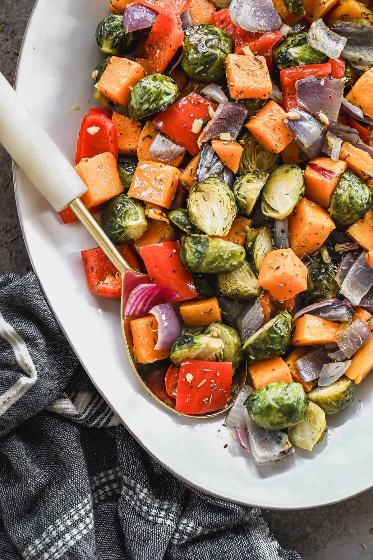 A gold serving spoon scooping up simple roasted vegetables.