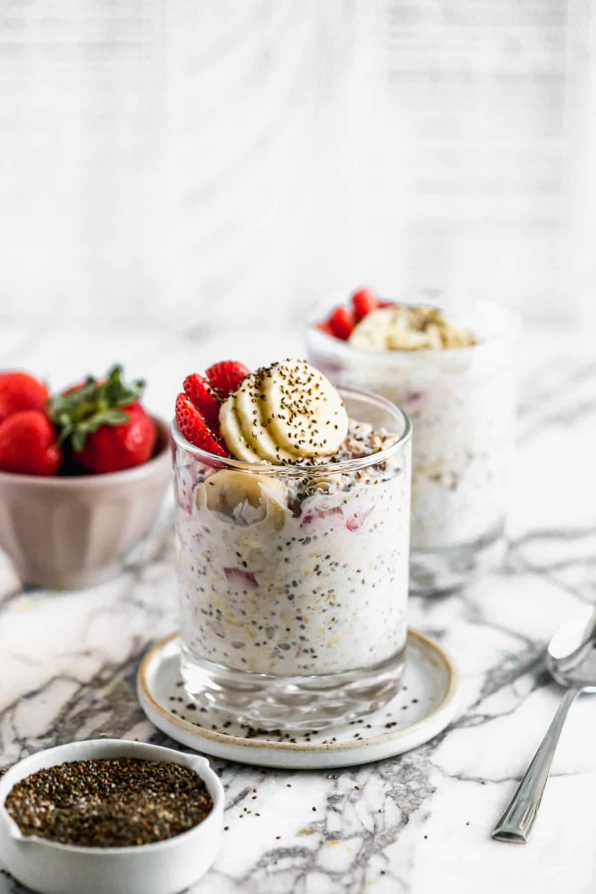 A strawberry overnight oats recipe topped with fresh strawberries and bananas, ready to eat.