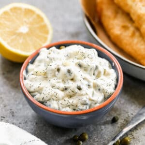 This homemade Tartar Sauce recipe in a small bowl with fish and chips in the background.