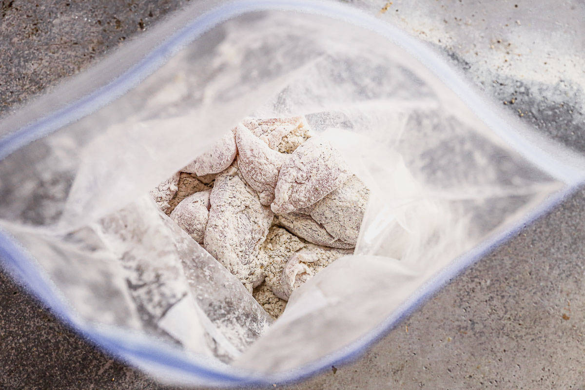 A ziploc bag filled with chicken tenders coated in flour, salt, pepper, basil, oregano, and onion powder.