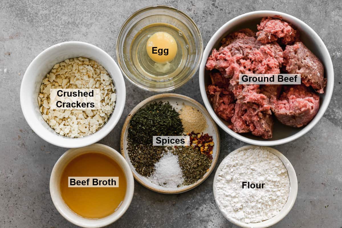 All of the ingredients needed to make the best air fryer meatballs: ground beef, egg, crackers, spices, beef broth, and flour.