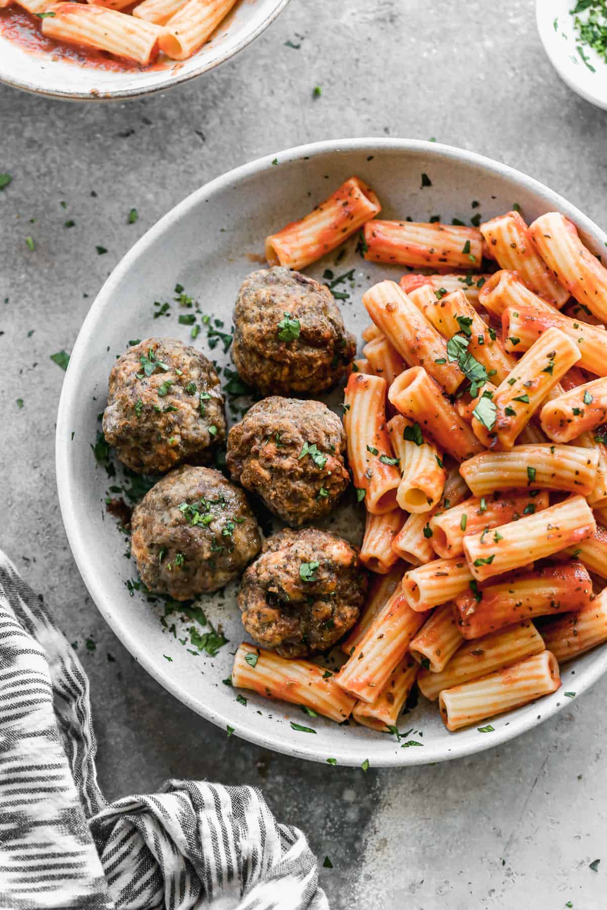 A plate of pasta with red sauce next to five homemade air fryer meatballs, ready to enjoy. 