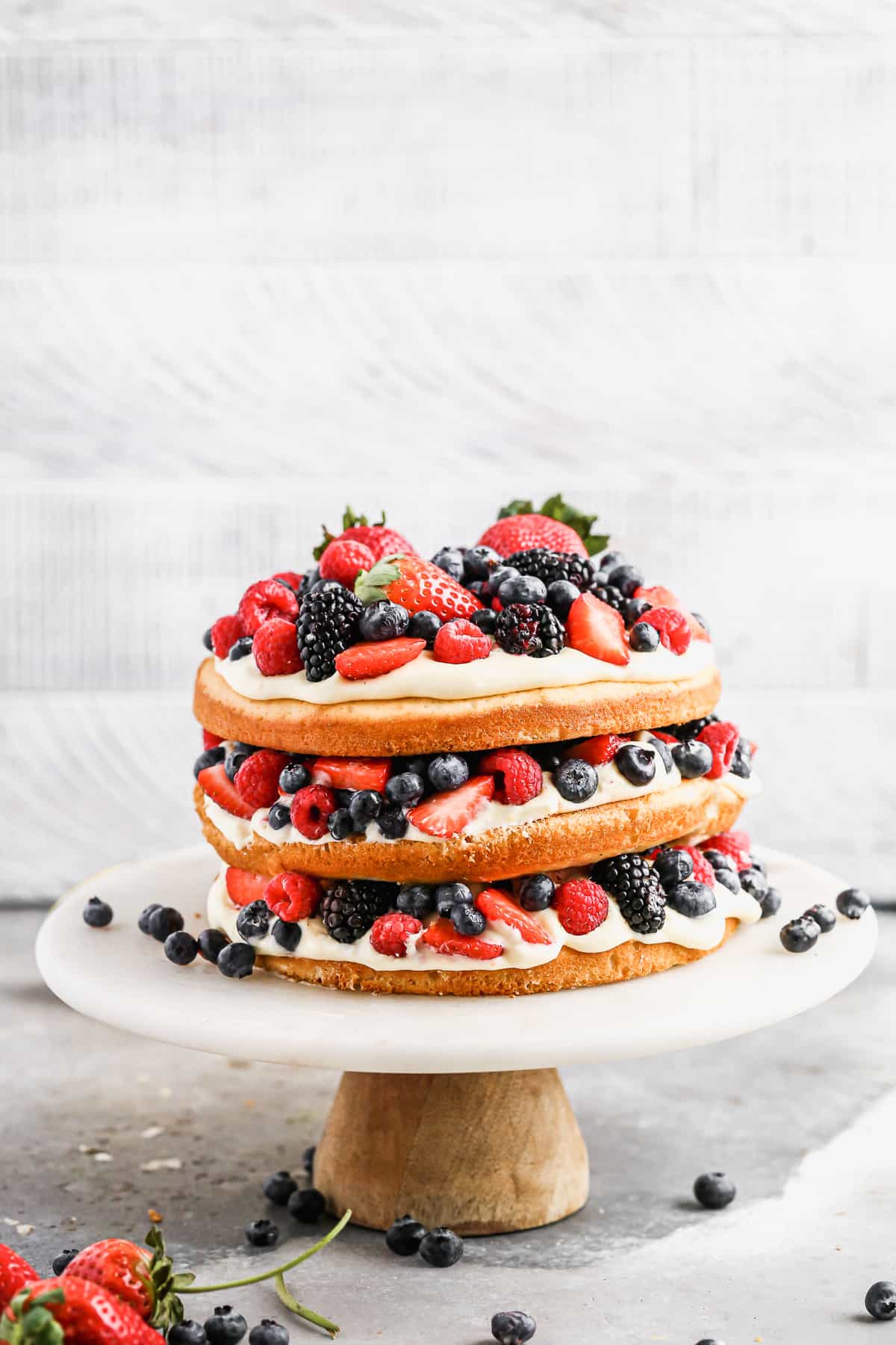 A fresh Berry Cake recipe with three tiers of yellow cake, topped with lemon mousse, and fresh berries.