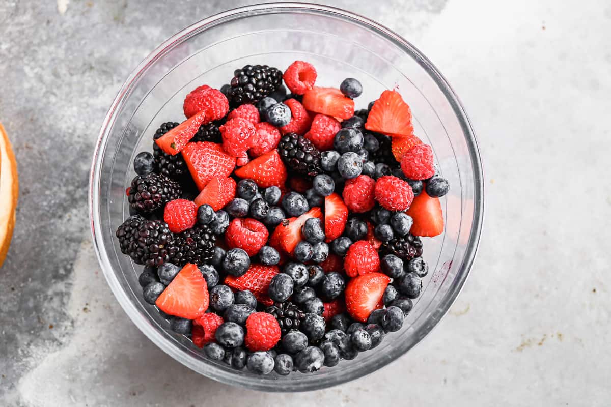 A bowl of fresh raspberries, blackberries, blueberries, and sliced strawberries.