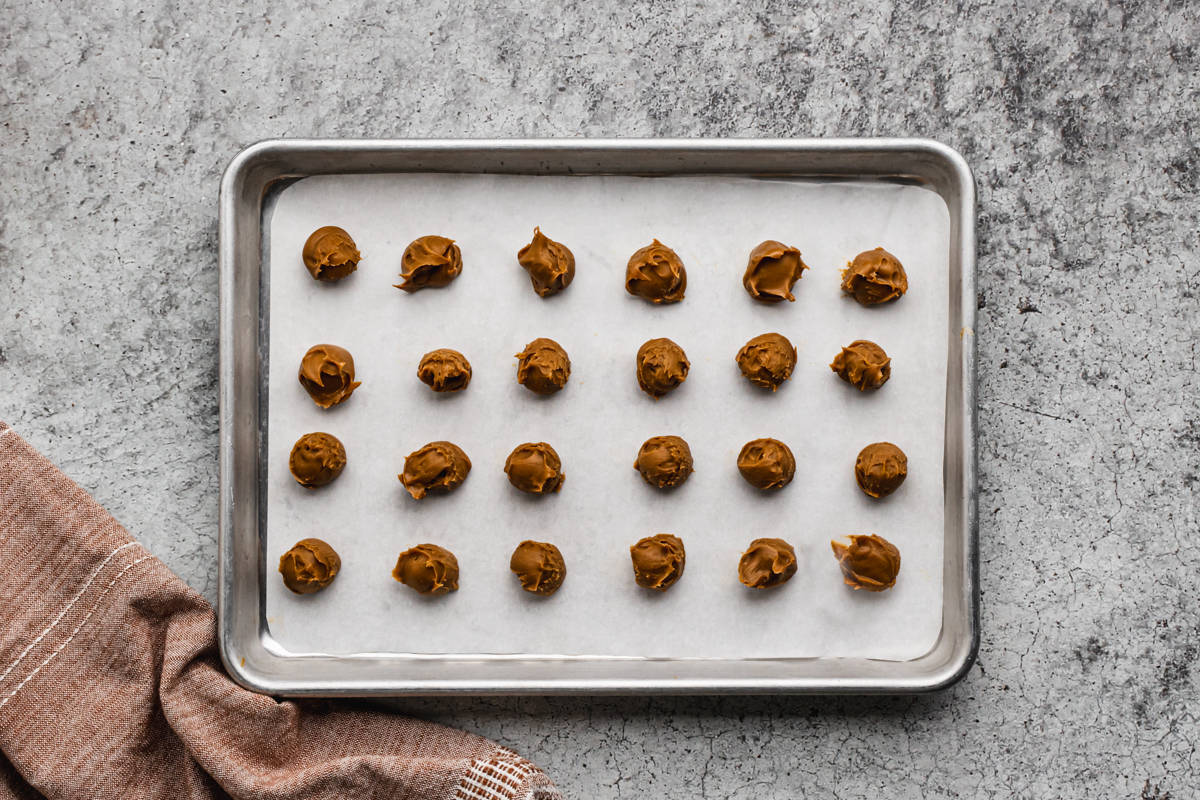 Little balls of biscoff cookie butter on a baking sheet.