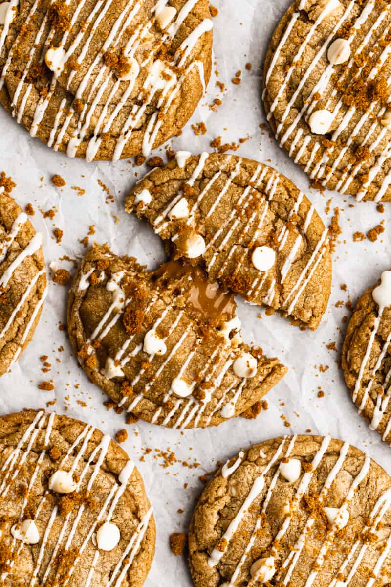 The best biscoff cookies recipe, drizzled with white chocolate and one cookie cut in half to show the cookie butter interior.