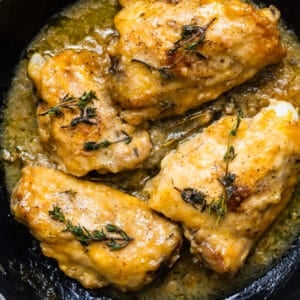 The best Chicken Marsala recipe in a cast iron pan, garnished with fresh thyme sprigs.