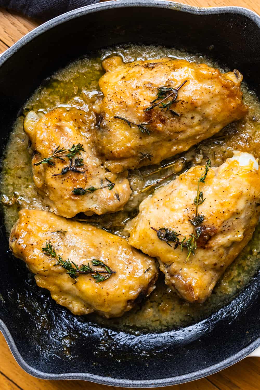 The best Chicken Marsala recipe in a cast iron pan, garnished with fresh thyme sprigs.