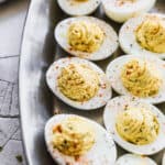 The best Deviled Eggs recipe on a silver platter, sprinkled with paprika and ready to enjoy.