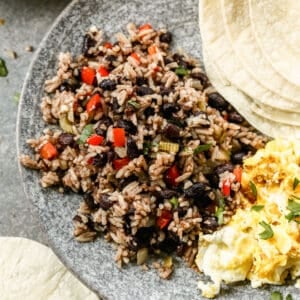 A delicious Gallo Pinto breakfast plate with a serving of gallo pinto, scrambled eggs, and a couple warm tortillas.