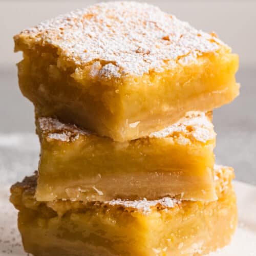 Three lemon bars, stacked, on a plate.