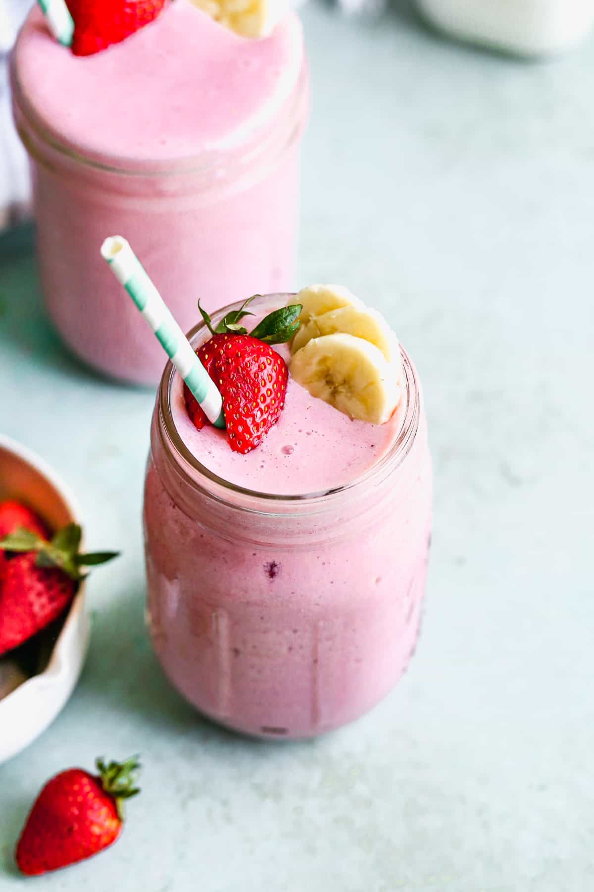 The best strawberry banana smoothie recipe with a strawberry, banana slices, and a straw ready to enjoy.