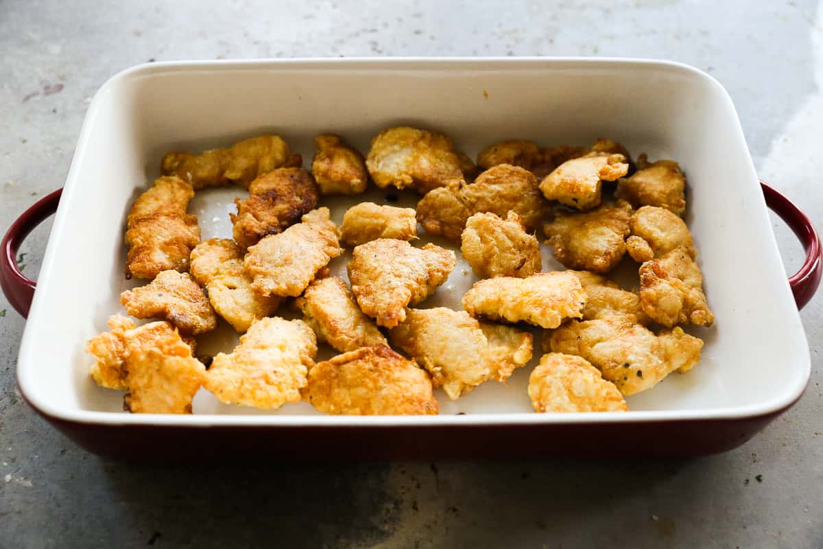 Homemade Sweet and Sour Chicken in a baking dish, ready to finish baking.