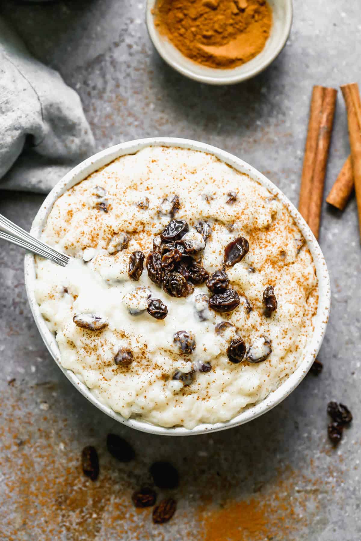 Arroz con Leche receta in a bowl with a dusting of cinnamon sugar and topped with some raisins.