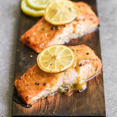 The best Cedar Plank Salmon recipe on a plank of cedar and topped with a brown sugar mustard glaze and a lemon on top.