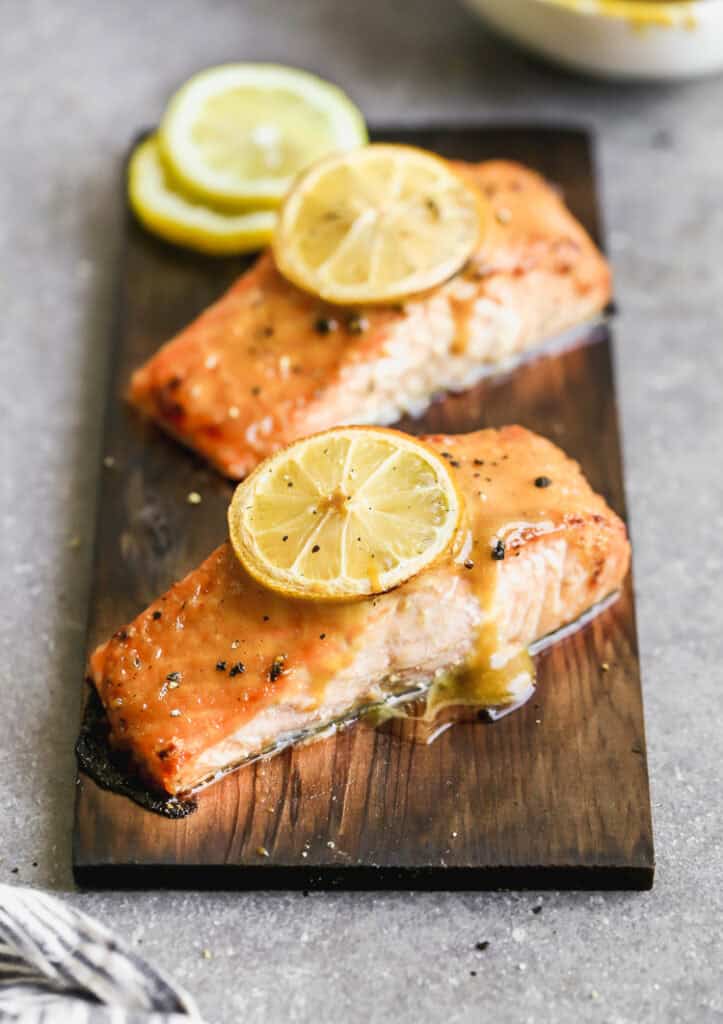 The best Cedar Plank Salmon recipe on a plank of cedar and topped with a brown sugar mustard glaze and a lemon on top.