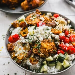 An easy Chicken Shawarma Bowl recipe with a bed of rice and topped with chicken, tomatoes, cucumber, and feta cheese.