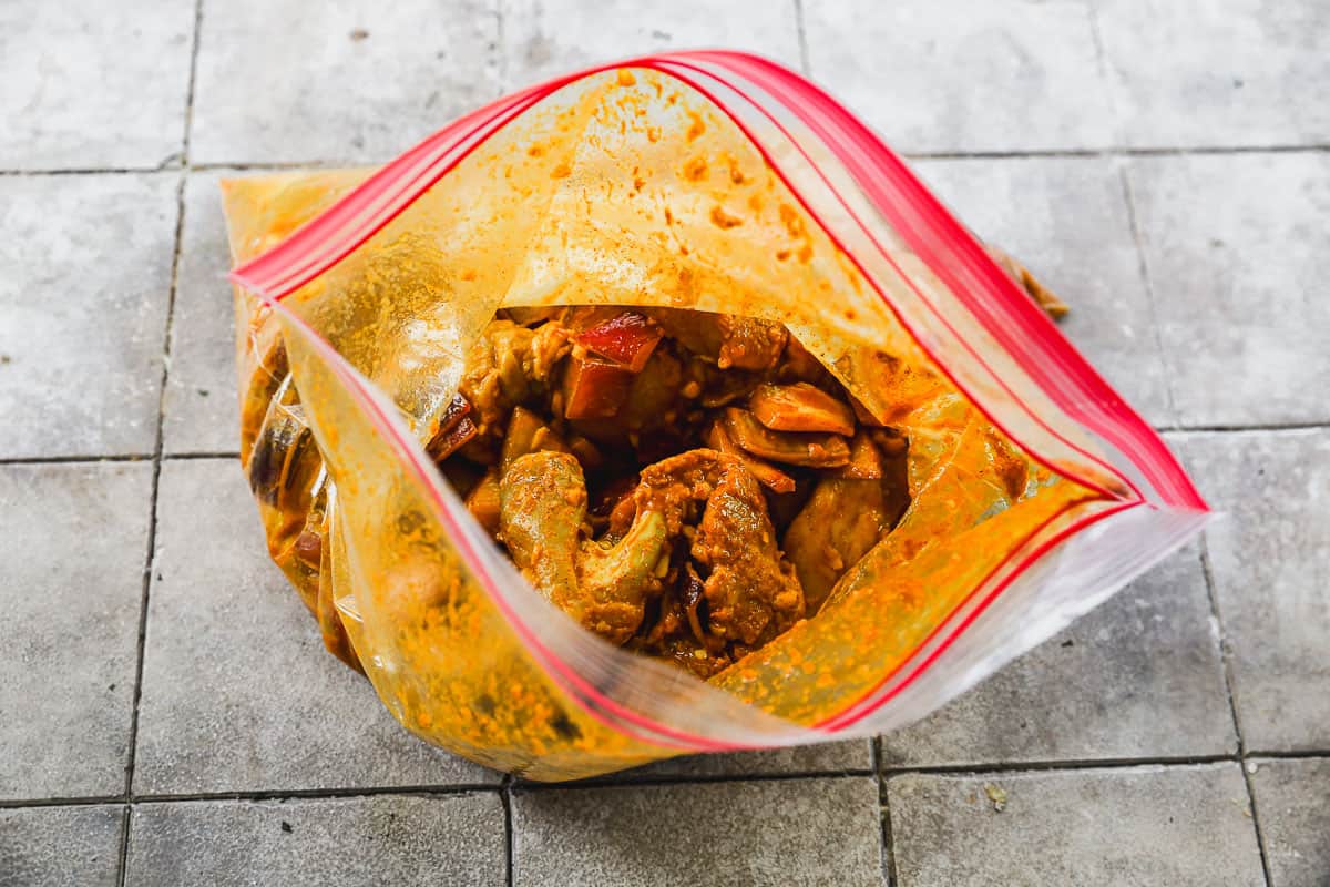 A bag filled with chicken thighs in a shawarma marinade.