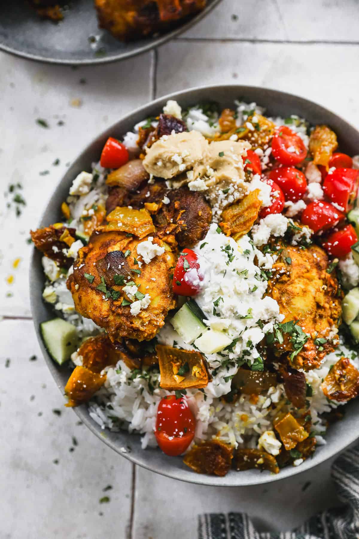 The best Chicken Shawarma Bowl with middle eastern inspired chicken on a bed of rice, topped with tomatoes, cucumber, feta cheese, and tzatziki sauce.