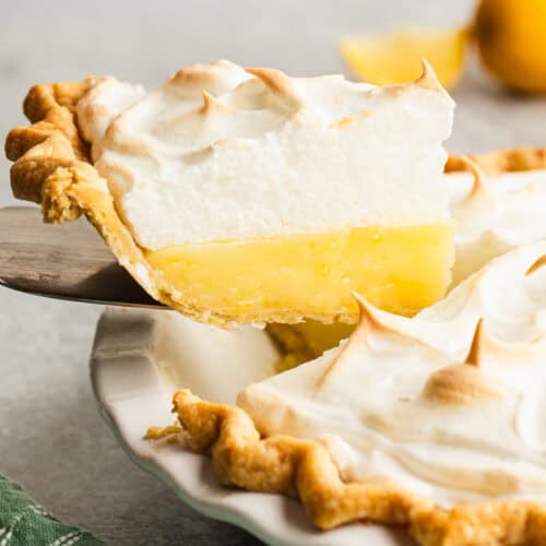 A slice of an easy lemon pie recipe being lifted out of the pie plate with a spatula, showing the lemon and meringue layers.