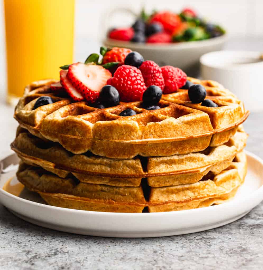 Three protein waffles stacked on top of each other and topped with fresh berries.