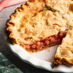 An old fashioned Rhubarb Pie recipe with a piece removed to show the homemade rhubarb filling.