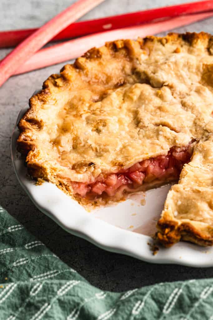 An old fashioned Rhubarb Pie recipe with a piece removed to show the homemade rhubarb filling.