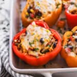 Easy vegetarian stuffed peppers in a baking dish, topped with melted cheese.