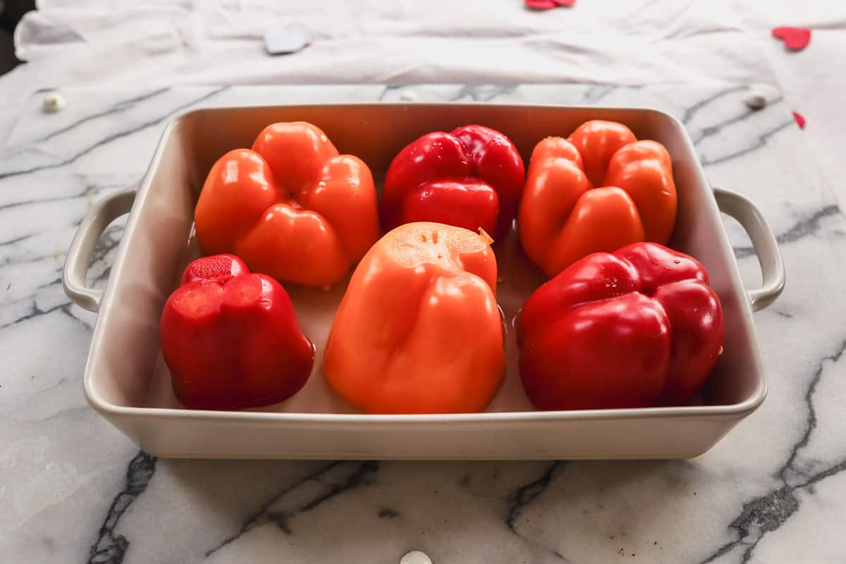 Six bell peppers upside down in water, being prepped for an easy stuffed peppers recipe.