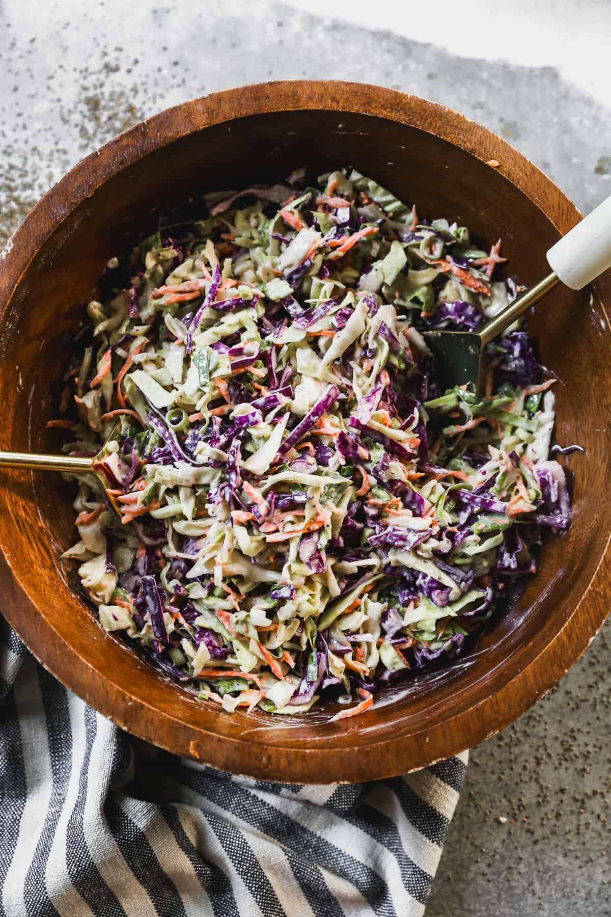 The best Coleslaw recipe with crunchy cabbage, green onions, carrots, and a creamy homemade dressing all tossed in a wooden bowl and ready to serve.