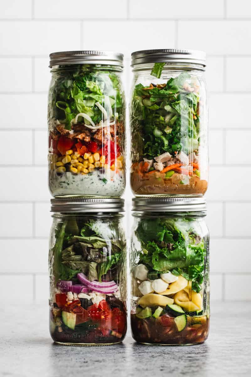 Four of the best Mason Jar Salad recipes in separate jars, stacked on top of each other.
