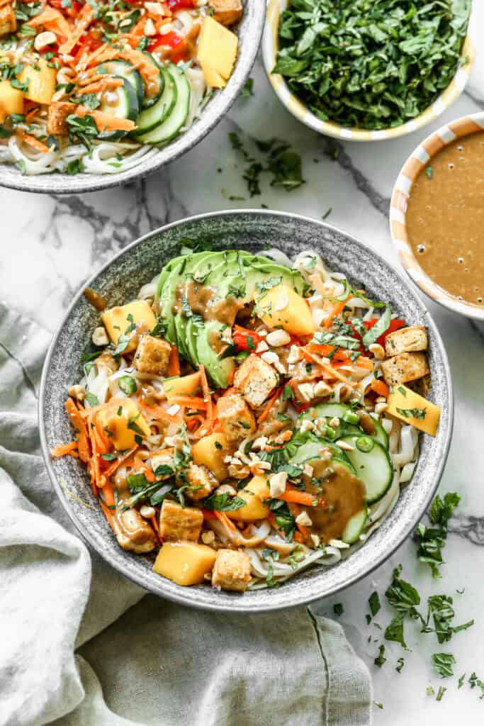 A homemade Spring Roll Bowl recipe with a sweet chili sauce, peanuts, avocado, carrot, bell pepper, cucumber, and mango.