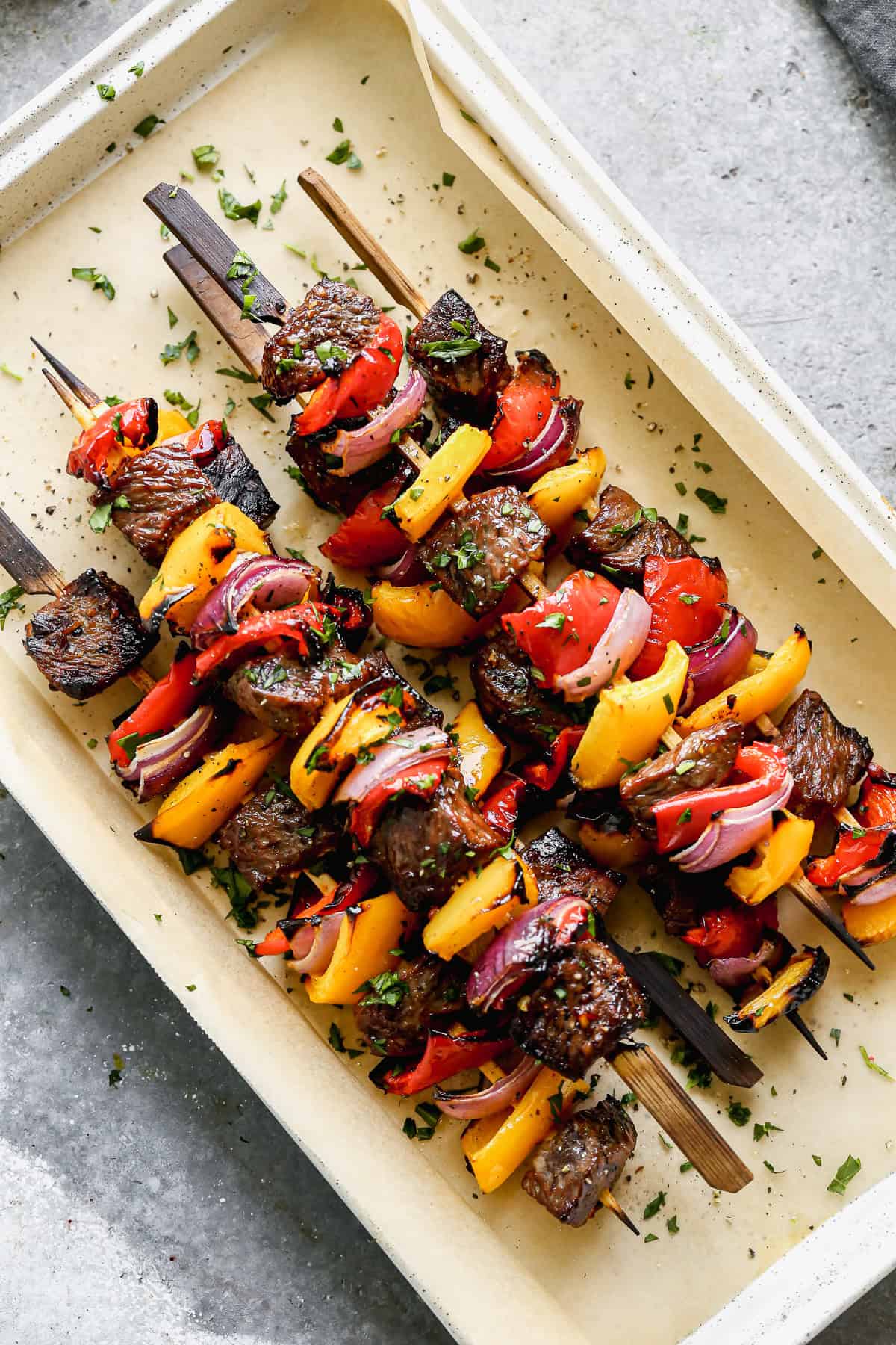 A pan of grilled Steak Kabobs with steak, red and yellow bell pepper, and red onion, ready to serve.