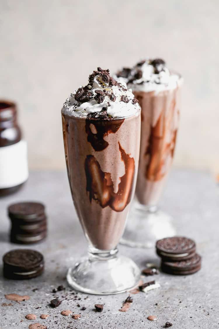 The best Oreo Milkshake recipe served in a tall milkshake glass, topped with whipped cream and crushed Oreos. 