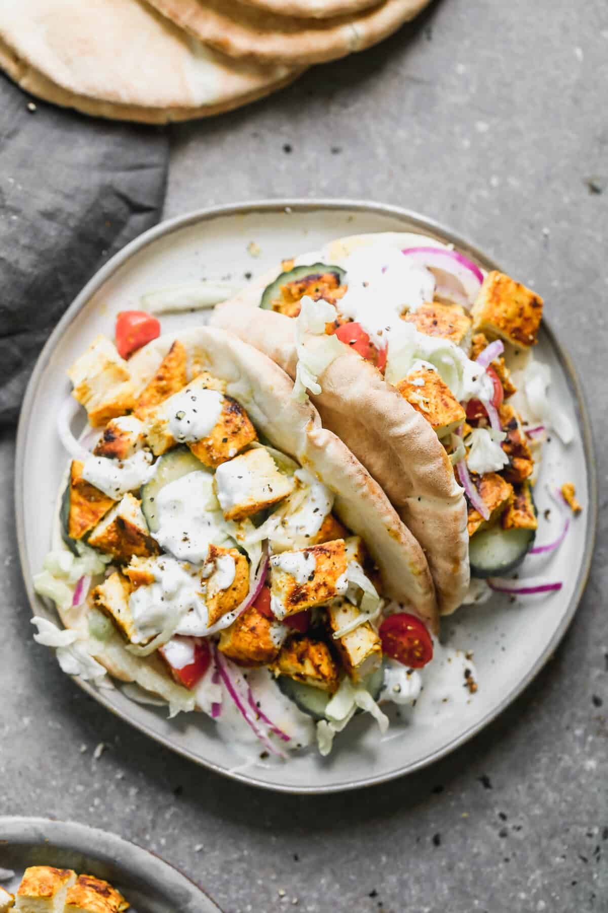 Two easy Chicken Gyros served on warm pitas and topped with chicken, cucumbers, onion, lettuce, and tzatziki sauce. 