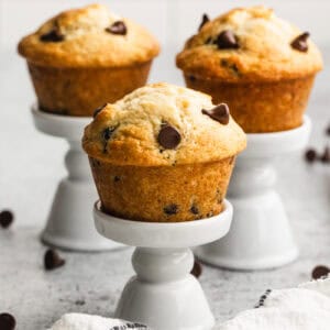 Three easy Chocolate Chip Muffins on top of little white muffin stands, ready to enjoy.